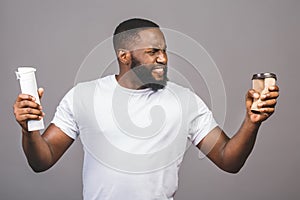 Zero waste concept. Young african american man making choose between cup of coffee and recycle one standing over isolated grey