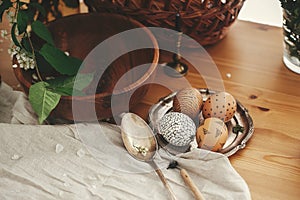 Zero waste Easter. Natural Easter eggs with modern wax ornaments on vintage plate on background of white spring flowers, candle,