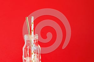 Zero waste. Paper recycable drinking cocktail party straws in glass vintage bottle on red background