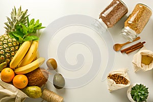 Zero waste and plastic free concept. Grocery shopping eco bag with fruits and cereals in glass jars, white background. Flat lay,