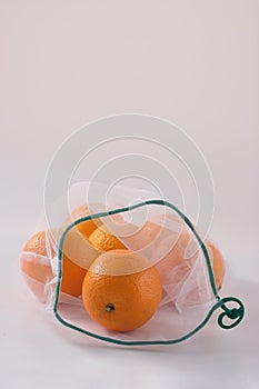 Zero waste, plastic free recycled textile produce bag for carrying fruit orange or vegetables, a white surface. Reusable using.