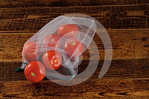 Zero waste, plastic free recycled textile produce bag for carrying fruit tomatos or vegetables, a wooden surface. Reusable using