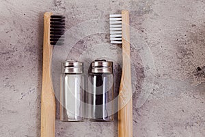 Zero waste self-care products. Black, white bamboo toothbrushe, and flax thread on grey concrete background