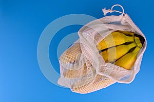 Zero waste shopping concept. Bananas in eco-cotton bags on a blue background. Plastic rejection concept. Copy space.