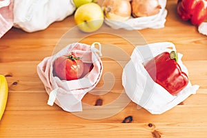 Zero Waste shopping concept. Fresh groceries in reusable eco bags and vegetables in plastic polyethylene bag on wooden table.