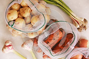 Zero waste shopping concept. fresh vegetables in eco cotton bags on table in the kitchen. lettuce, corn, potatoes