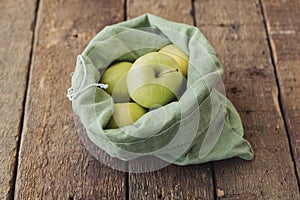 Zero waste shopping. Fresh apples in eco cotton bag on rustic wood. Eco sustainable lifestyle