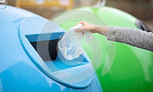 Zero Waste. Woman throwing single use plastic bag into blue recycle bin