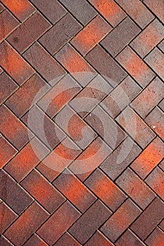 Zigzag pattern of red and brown paving tiles close up