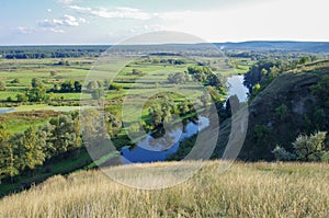 Zigzag river flows between summer valleys