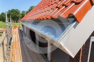 Zinc rain gutter with roof tiles and scaffolding