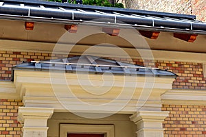 zink gutter. building elevation closeup. brick house facade with gray zink sheet roof