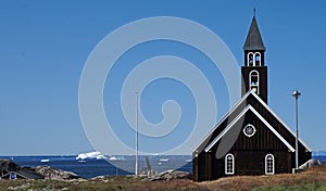 Zion\'s Church on the shore in front of the sea with ice from the icebergs, Ilulissat, Greenland