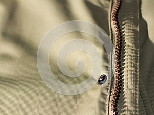 Zipper on beige workwear protective clothing in close-up.