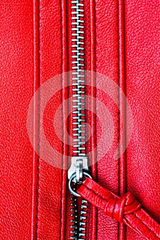 Zipper partly open close up detail macro photo on a red leather texture background in vertical format