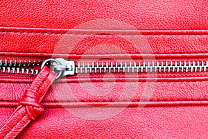 Zipper partly open close up detail photo on a red leather texture background