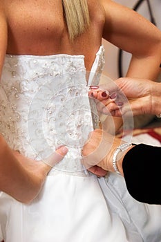 Zipping up brides dress photo
