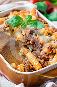 Ziti bolognese in baking dish. Pasta casserole with minced meat, tomato sauce and cheese, vertical