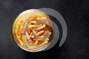 Ziti rigati or tubini pasta in a jar on black background