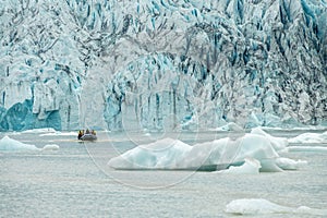 Zodiac boat among icebergs in Fjallsarlon glacier lagoon, arctic landscape Iceland