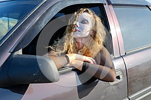 A zombie girl with black eyes and a bloody mouth in the car