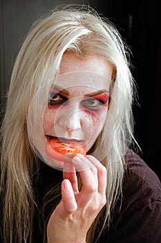 Zombie girl with black eyes and a bloody mouth on Halloween