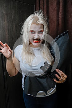 Zombie girl with black eyes and a bloody mouth on Halloween