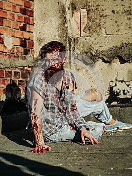 Zombie man sits on asphalt