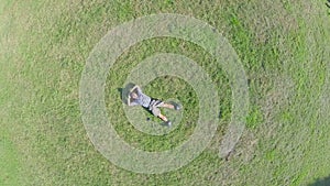 Zoom-in aerial vertical view of young guy sleeping on grass