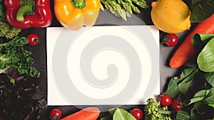 Zoom in fresh organic vegetables setting on table and blank white paper for text, Healthy food concept top view. Slow motion.