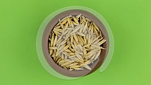 Zoom out, rotation of oat grains in a clay pot, isolated