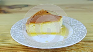 Zoom out from small piece of milk soft flan with caramel syrup on round plate