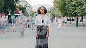 Zoom out time lapse of African American lady in stylish clothing in city street