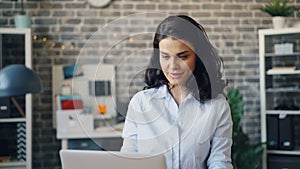 Zoom-in portrait of attractive office manager using computer then smiling