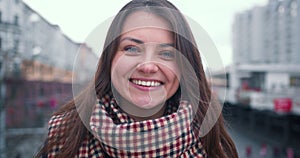 Zoom in portrait of beautiful happy excited 30-35 brunette Caucasian woman smiling at camera in city street slow motion.