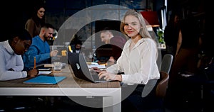 Zoom in portrait of beautiful successful young Caucasian blonde business woman smiling at camera at modern loft office.