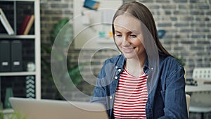 Zoom in portrait of beautiful young lady using laptop at work then smiling