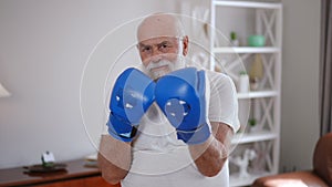 Zoom in portrait of confident inspired senior boxer raising hands in boxing gloves looking at camera. Positive motivated