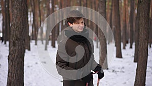 Zoom in portrait of smiling teenage Caucasian boy looking away standing in winter park turning in slow motion. Happy