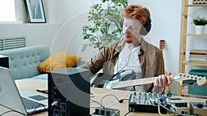 Zoom-in portrait of talented musician playing guitar and composing music taking notes at home