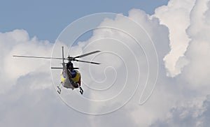 Zoom in shot of a Helicopter or Chopper hovering mid air with cloudy blue sky in the background for Rescue concept