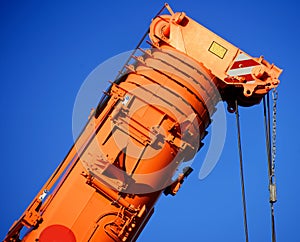 Zoom shot of an orange-coloured truck-mounted crane with telescopic boom pushed together