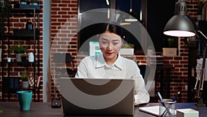 Zoom in on smiling businesswoman inputting data on laptop