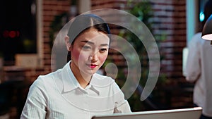 Zoom in on smiling businesswoman inputting data on laptop