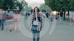 Zoom-in time lapse of beautiful young woman standing outdoors in urban street