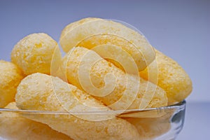 Zoomed Corn Puffs in a Glass Bowl. Crunchy Flavored Puffed Snacks. Party, Movie Snacks