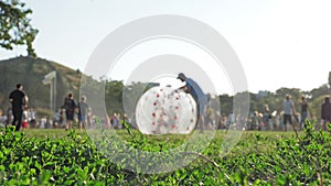 zorbing. zorb ball. inflatable ball. People are having fun. Man is rolling happy child inside large tarsparent