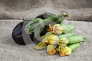 Zucchini and eggplant on wooden background and sack