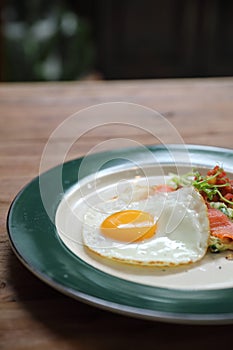 Zucchini fritters with egg and smoked salmon on wood background vinage style