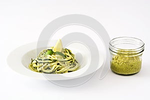 Zucchini noodles with pesto sauce on white background